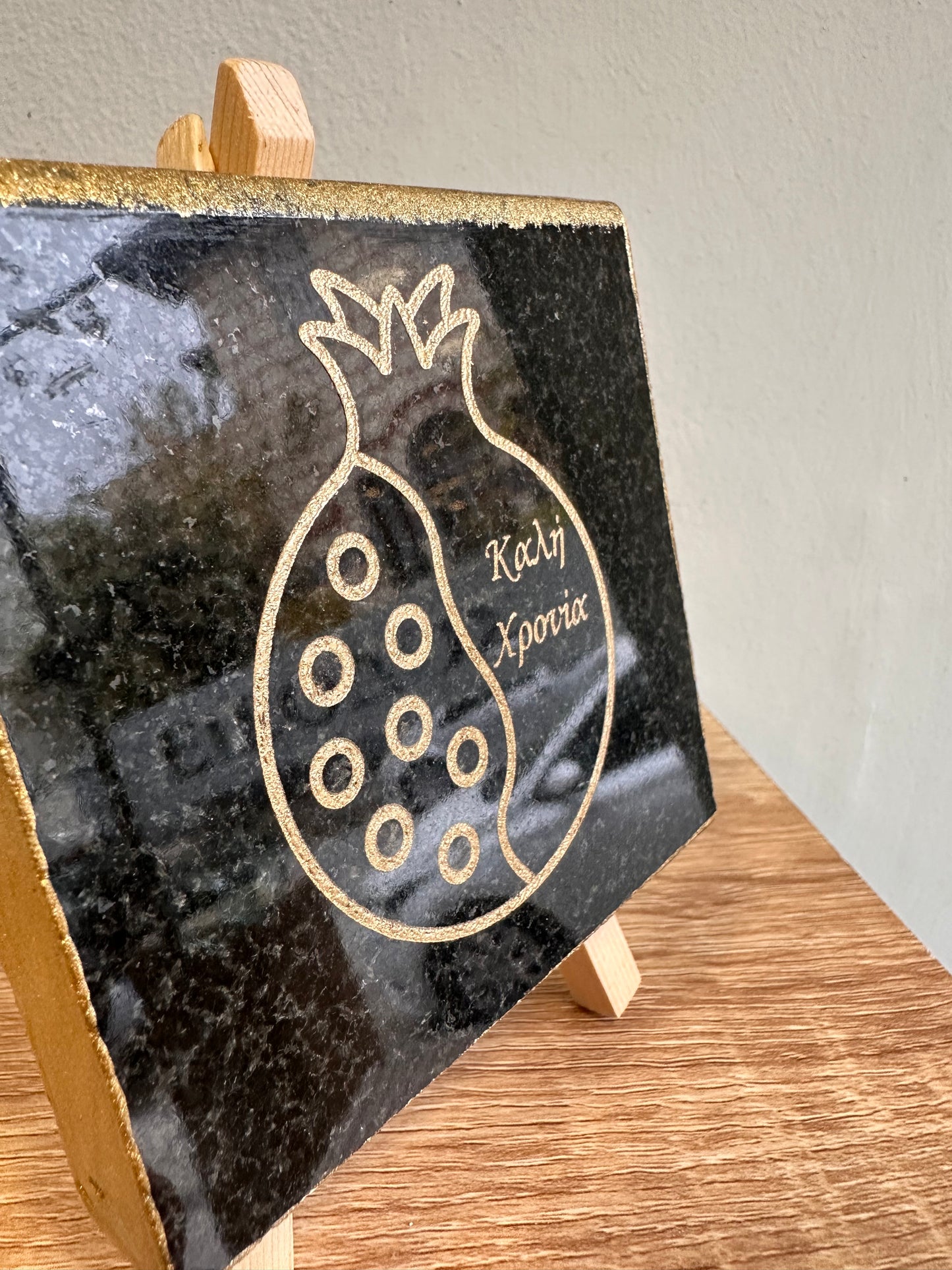 Γούρι ρόδι καλή χρόνια χαραγμένο σε μαύρο γρανίτη με χρυσά γράμματα και ξύλινη βάση