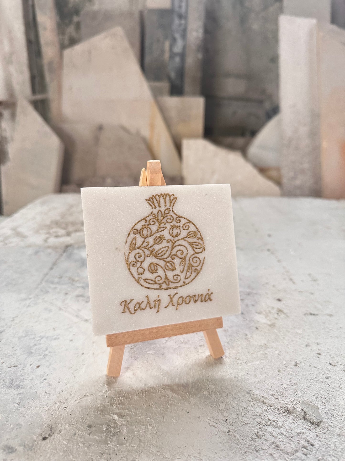 Good luck pomegranate charm engraved in white marble with gold letters on a wooden base