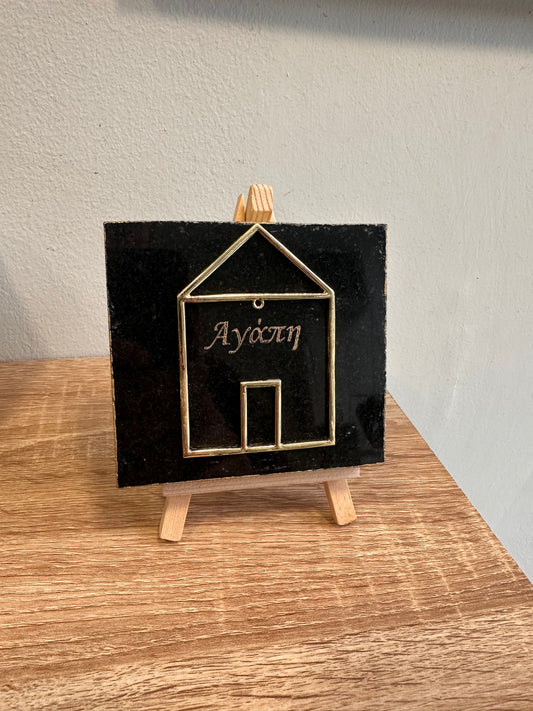 Charm with a metal house engraved on black granite with gold letters and a wooden base