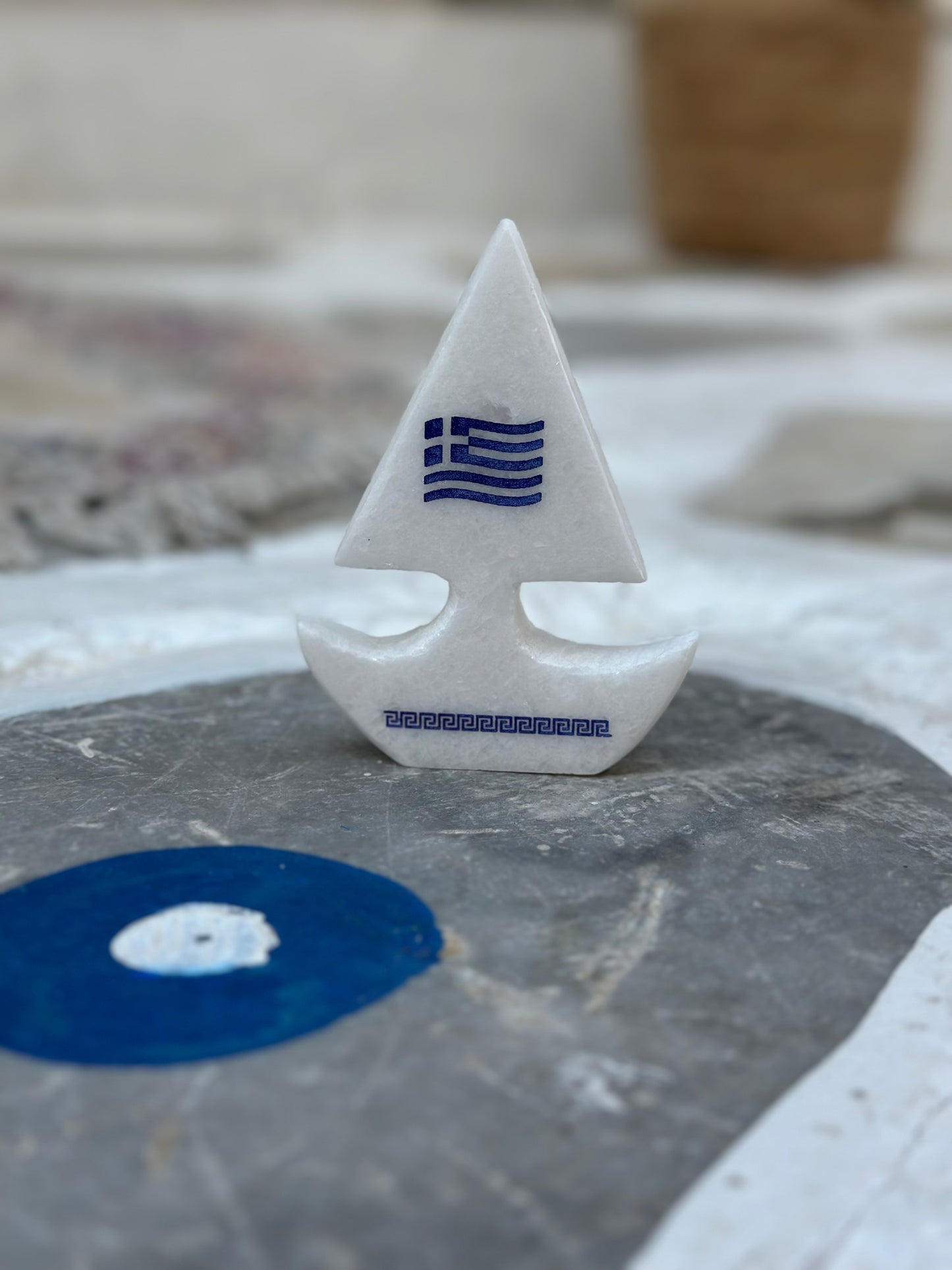 Καραβάκι από λευκό μάρμαρο με χάραξη την ελληνική σημαία και τον μαίανδρο